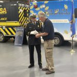 EMSA Honor Guard member Zach Sinsheimer hands token of appreciation to Jim Vitaletti